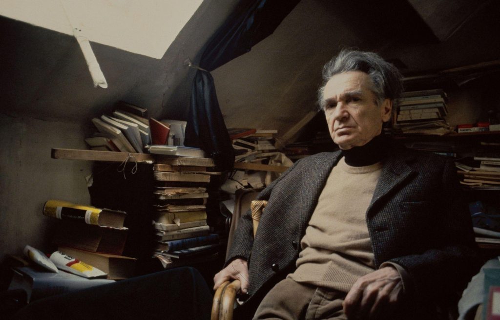 Emil Cioran, filósofo rumano, sentado en su estudio rodeado de libros y papeles apilados