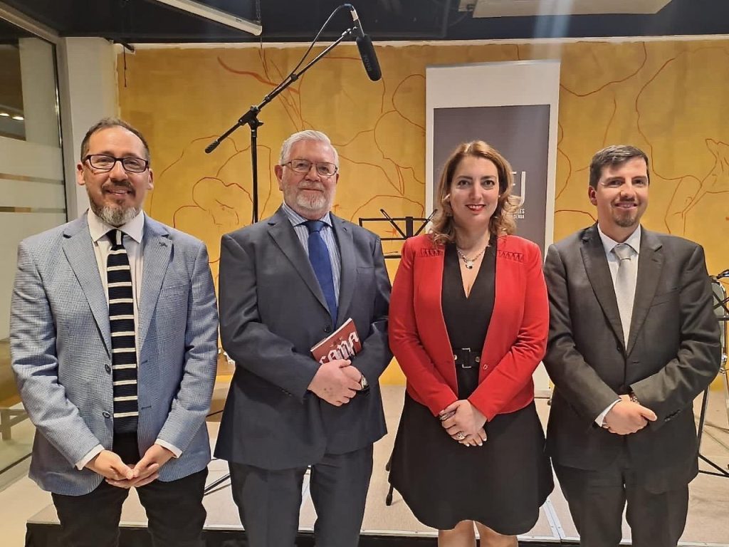 Cuatro profesionales en estudio de grabación con micrófono, pared amarilla de fondo, durante discusión sobre justicia