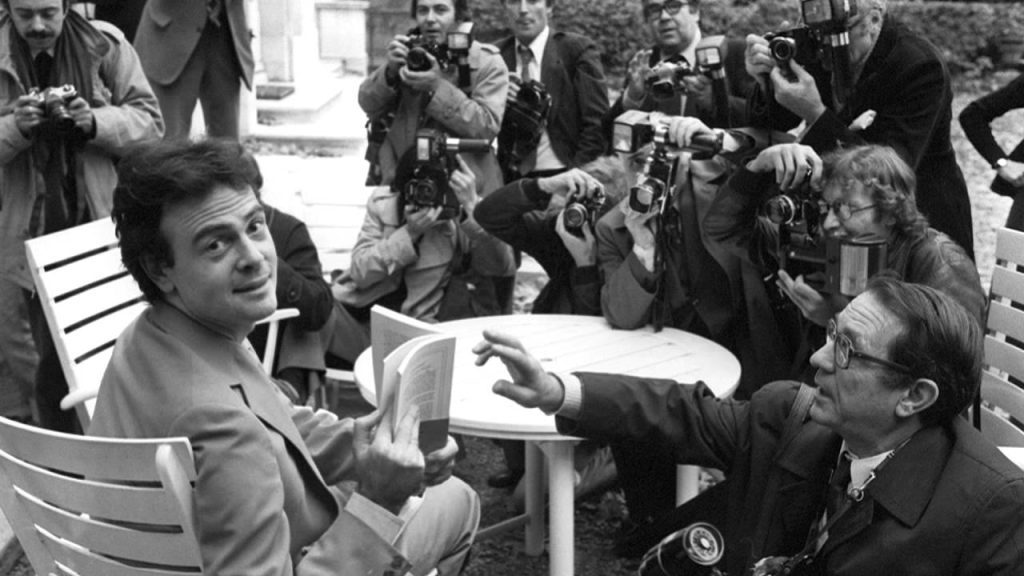Patrick Modiano firma autógrafos rodeado de periodistas y fotógrafos en evento público de gran concurrencia