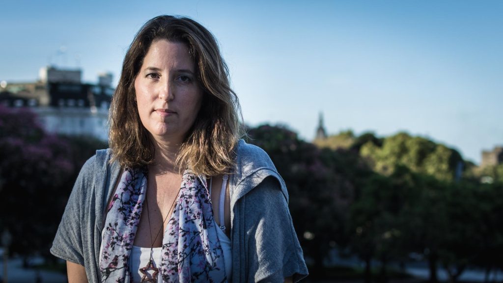 Agustina Bazterrica, autora argentina, retratada al aire libre con fondo urbano y vegetación
