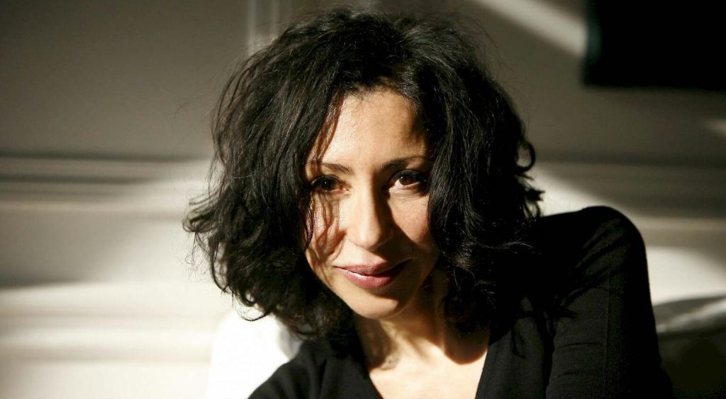 Yasmina Reza, dramaturga francesa, con cabello largo oscuro y expresión seria, fotografiada en interiores