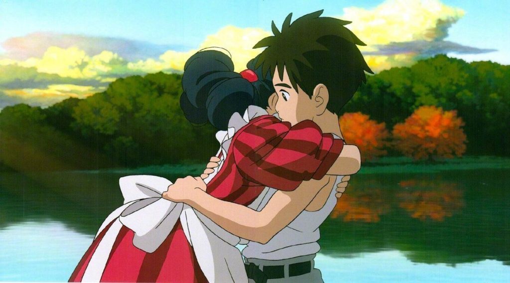 Joven abraza a una niña de cabello rojo frente a un río al atardecer con montañas de fondo