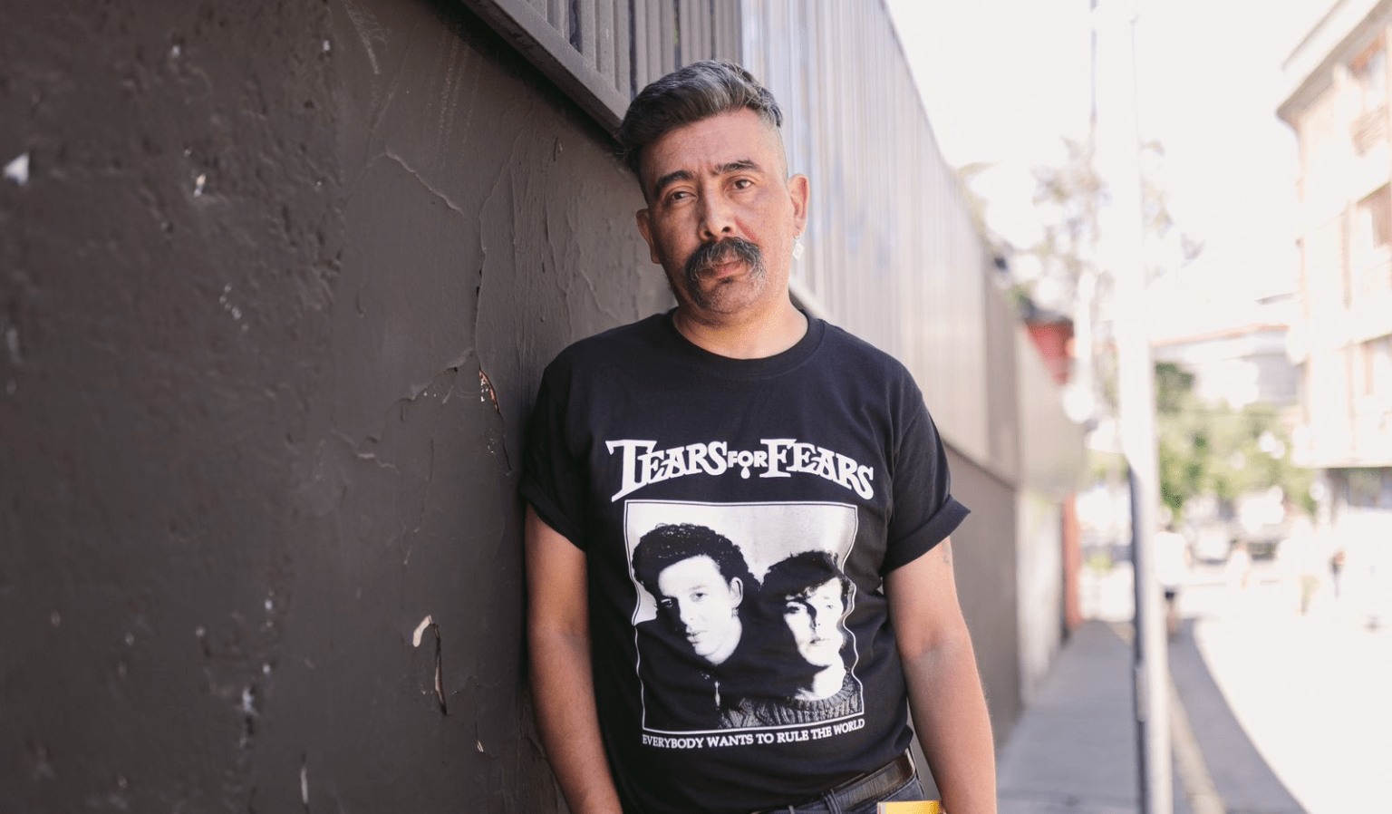 Marcelo Arce Garín, hombre de mediana edad con bigote, viste camiseta negra con gráfica blanca, junto a pared gris
