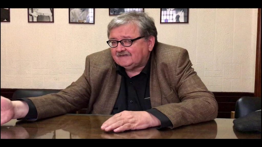 Jorge Calvo, hombre de mediana edad con gafas y blazer marrón, sentado ante una mesa en una sala