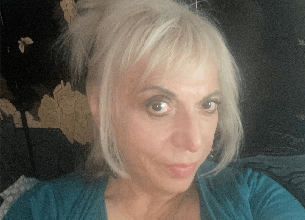 Natasha Valdés, escritora, retrato con cabello rubio corto y blusa azul oscuro
