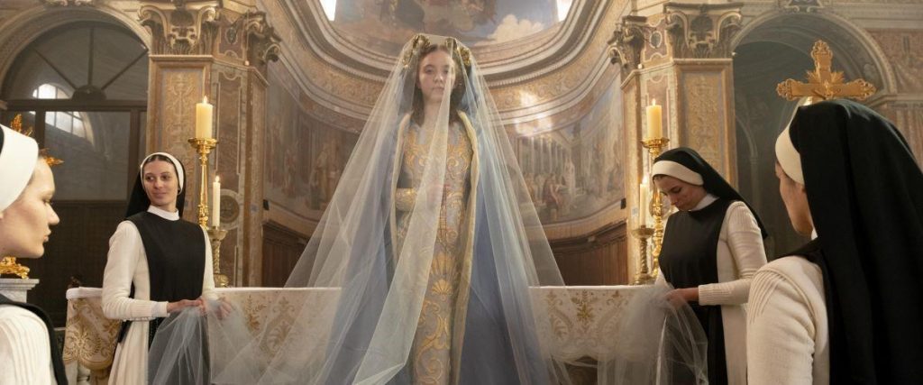 Escena de película religiosa: mujer con velo blanco en altar de iglesia ornamentada, rodeada de figuras en hábitos