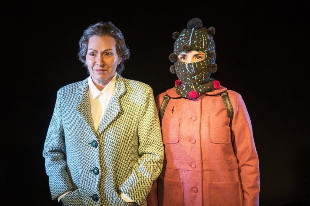 Gabriela Mistral junto a actriz con máscara de personaje en escena teatral de montaje sobre la poeta chilena