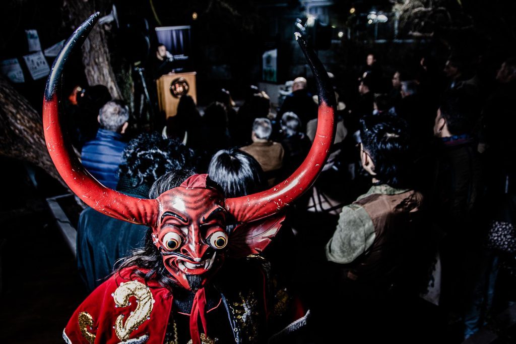 Performer en traje rojo de diablo con cuernos iluminados en exposición sobre identidad cultural del Norte Grande