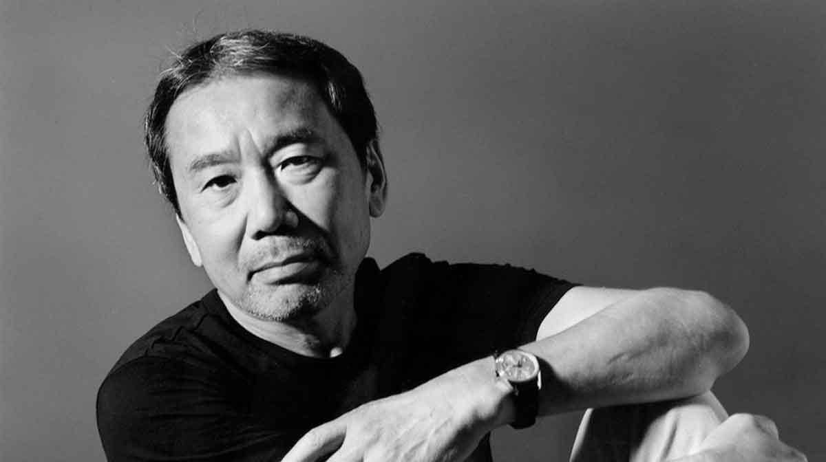 Haruki Murakami, escritor japonés, en retrato fotográfico en blanco y negro apoyando su brazo en la mesa