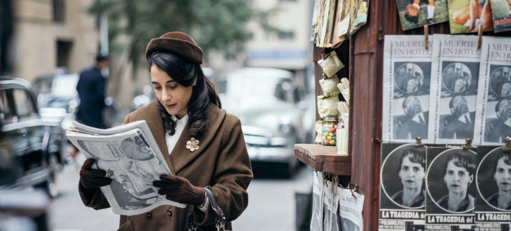 Mujer leyendo periódico en la calle junto a vitrinas con fotografías en blanco y negro, ambiente urbano de ciudad