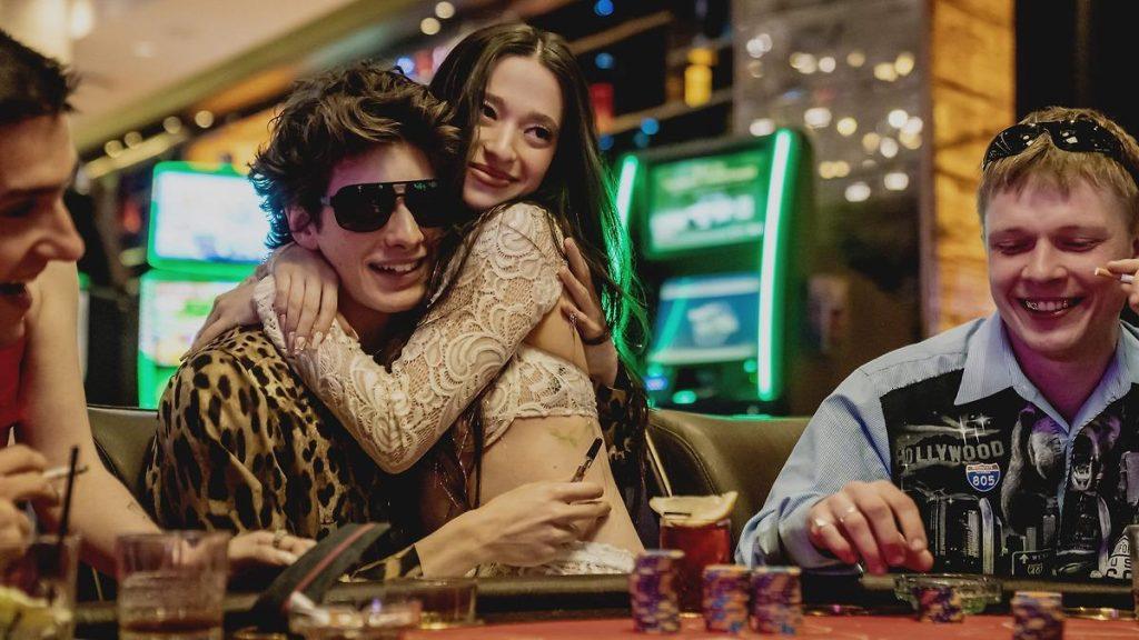 Grupo de personas alrededor de una mesa de juego en un casino, con luces de neón verde de fondo y atmósfera lujosa
