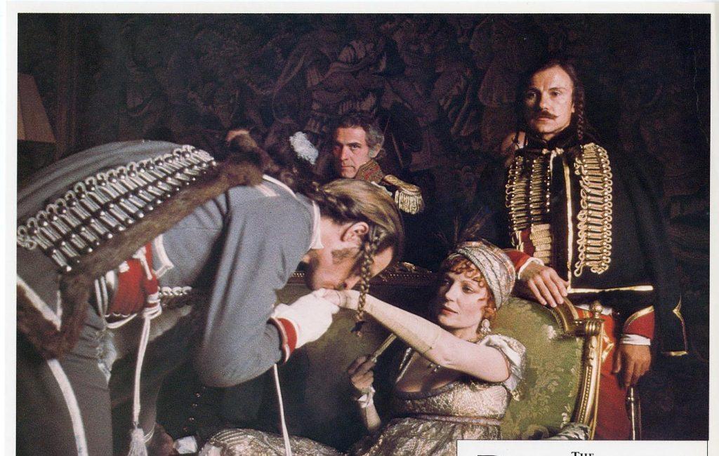 Escena de película clásica: grupo de actores en interior oscuro, hombre de uniforme militar con cordones dorados de pie