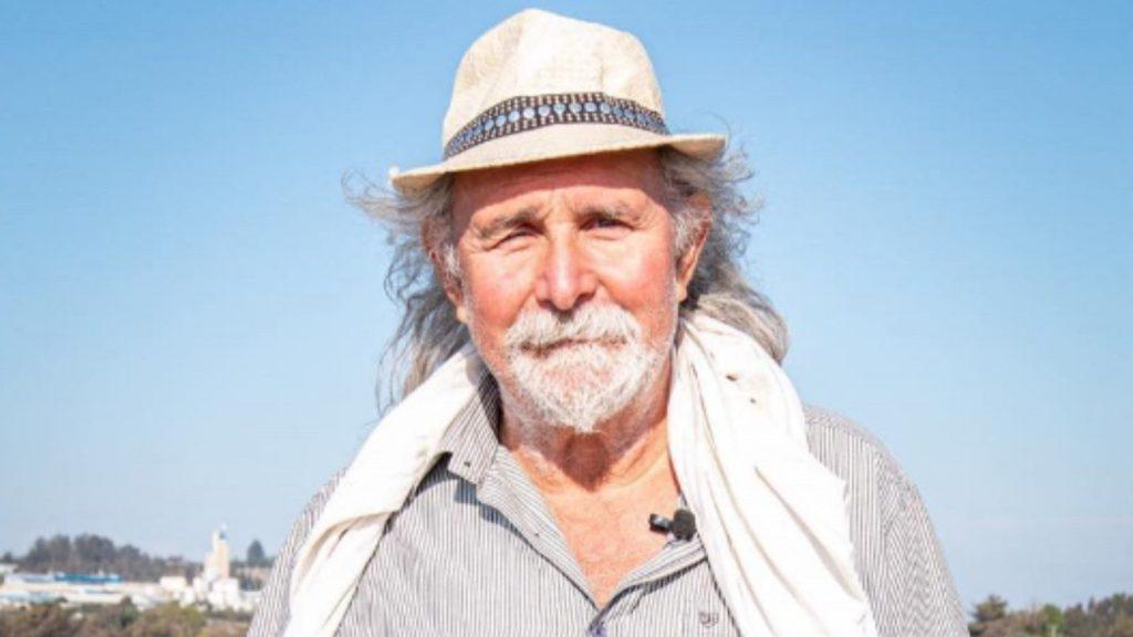 Erick Pohlhammer, poeta chileno con sombrero blanco, bufanda y camisa, retrato en exteriores