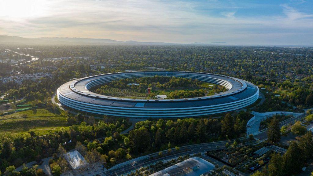 Edificio circular futurista de vidrio azul rodeado de vegetación y lagos, arquitectura sostenible en entorno natural