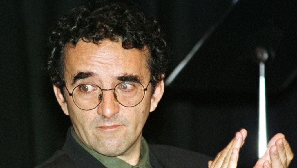 Roberto Bolaño, escritor chileno, con gafas y micrófono, durante una presentación o evento cultural