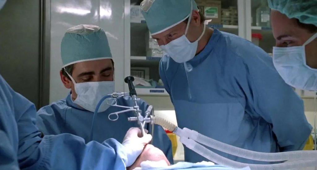Cirujanos con mascarilla y bata quirúrgica realizan una intervención médica en sala de operaciones