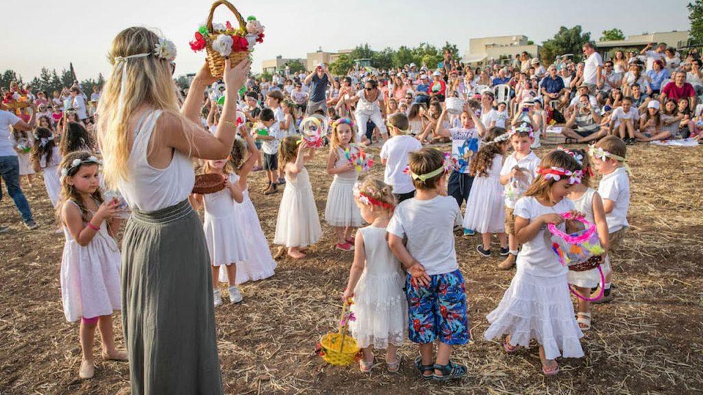 Celebración de Shavuot en Israel con mujeres y niños en campo abierto, participantes en trajes tradicionales blancos