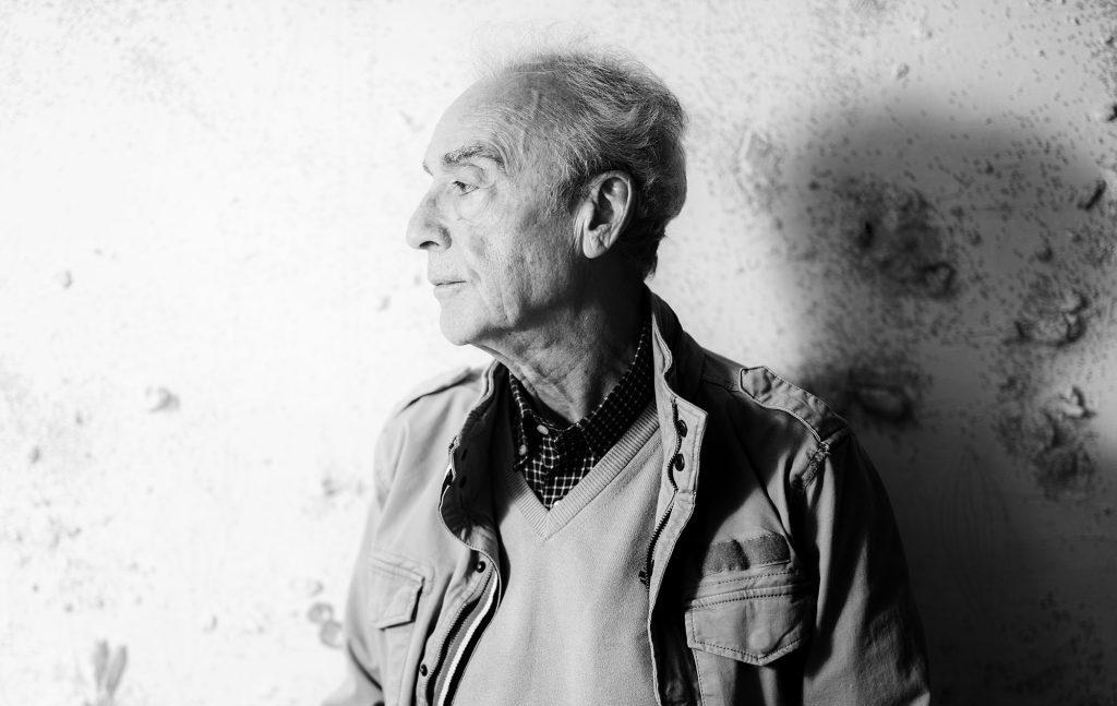 Hombre mayor de perfil, con cabello gris, mirando hacia la izquierda en fotografía en blanco y negro