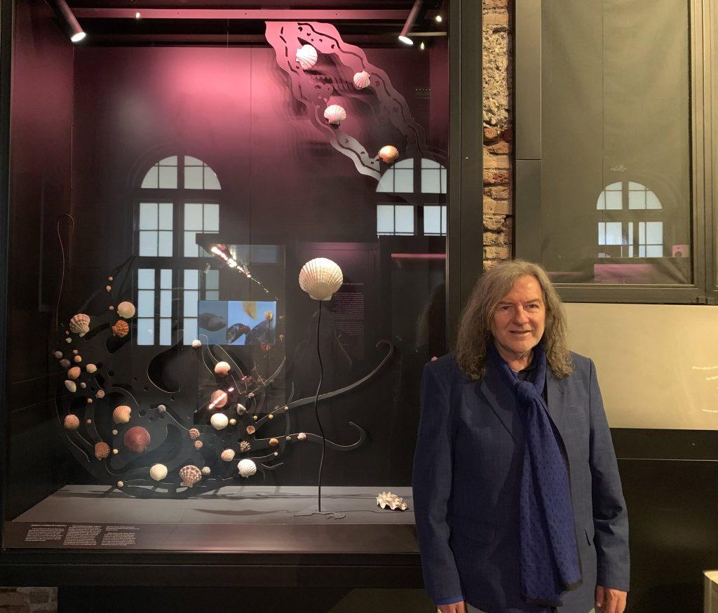 Mujer junto a vitrina con escenografía nocturna, barco iluminado y decoraciones navideñas en museo o galería