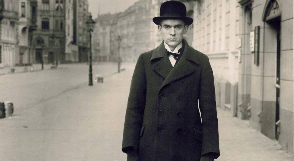 Hombre de traje oscuro y sombrero en una calle urbana vacía de principios del siglo XX