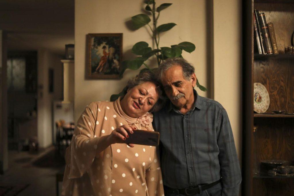 Dos personas abrazan en una sala de estar acogedora con libros y plantas al fondo