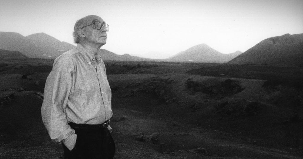 Hombre de perfil en paisaje desolado de lava volcánica, mirando hacia el horizonte montañoso en fotografía blanco