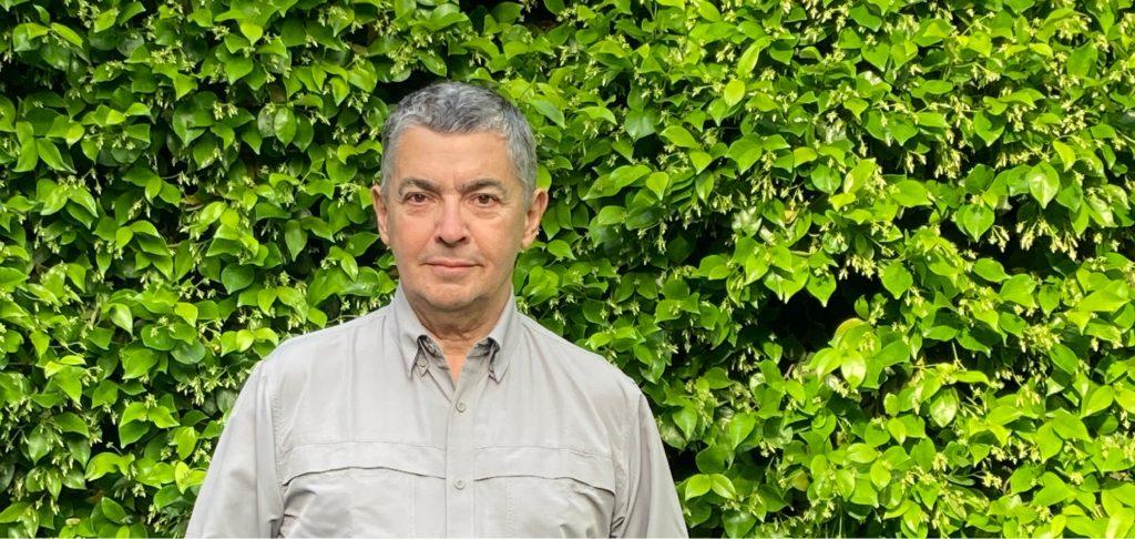 Pablo Errázuriz, escritor chileno, sonríe frente a una pared cubierta de hiedra verde