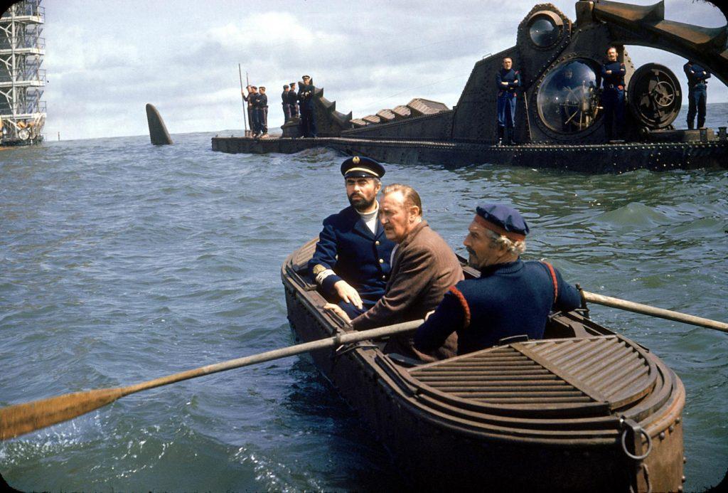 Oficiales navales en bote remando hacia un buque submarino en aguas profundas