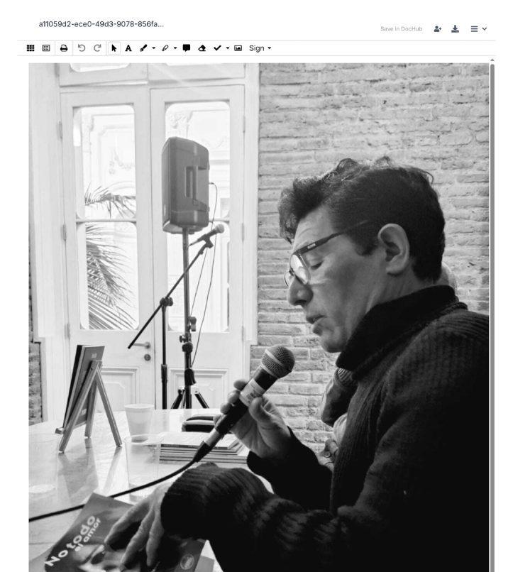 Iván Quezada hablando ante un micrófono en estudio de grabación, con ventana y pared de ladrillo al fondo