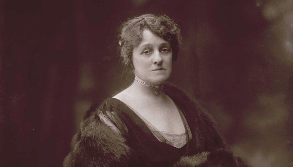 Retrato de Edith Wharton, autora estadounidense, con abrigo de piel y fondo oscuro, principios del siglo XX