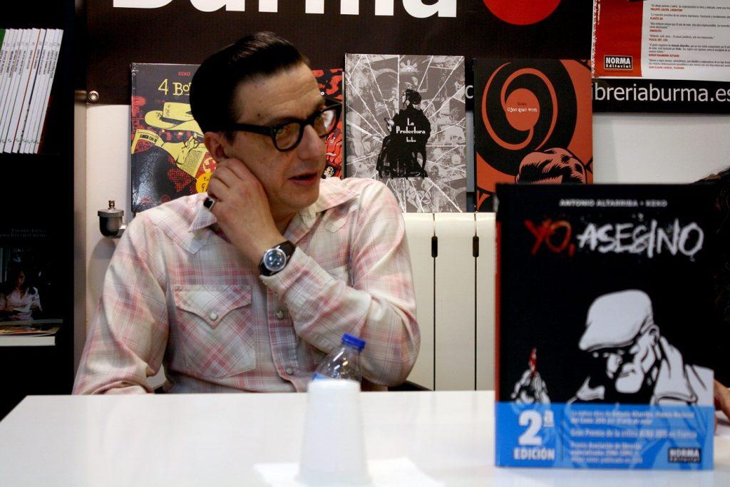 Keko con gafas de sol en estudio de radio, micrófono y posters de películas al fondo