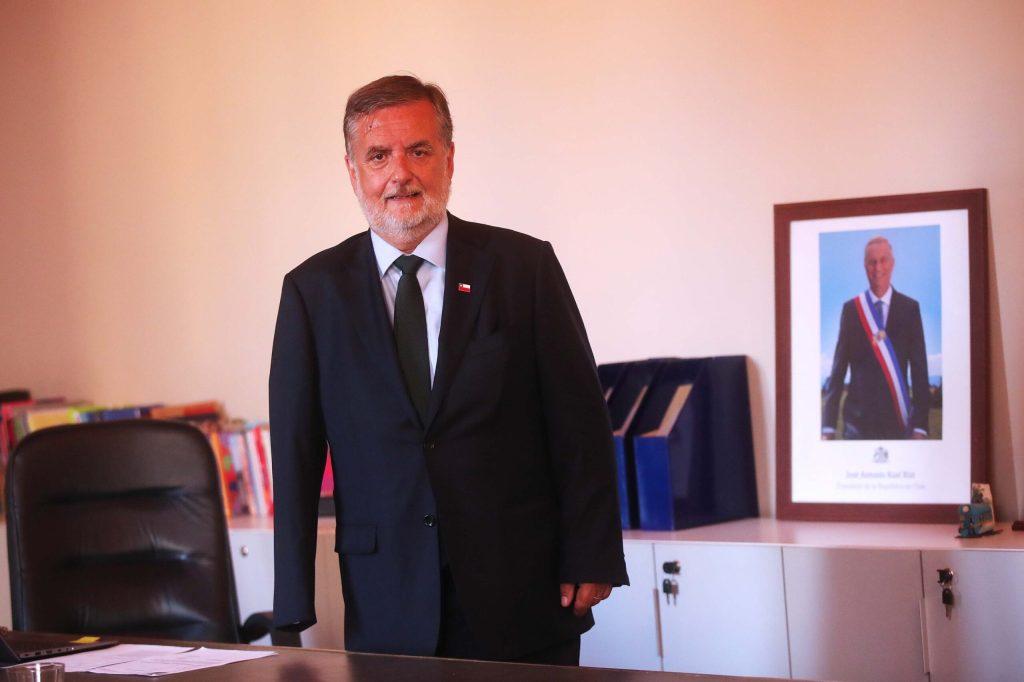 Pedro Pablo Undurraga, de traje y escarapela tricolor, posa en una oficina junto a un retrato presidencial enmarcado
