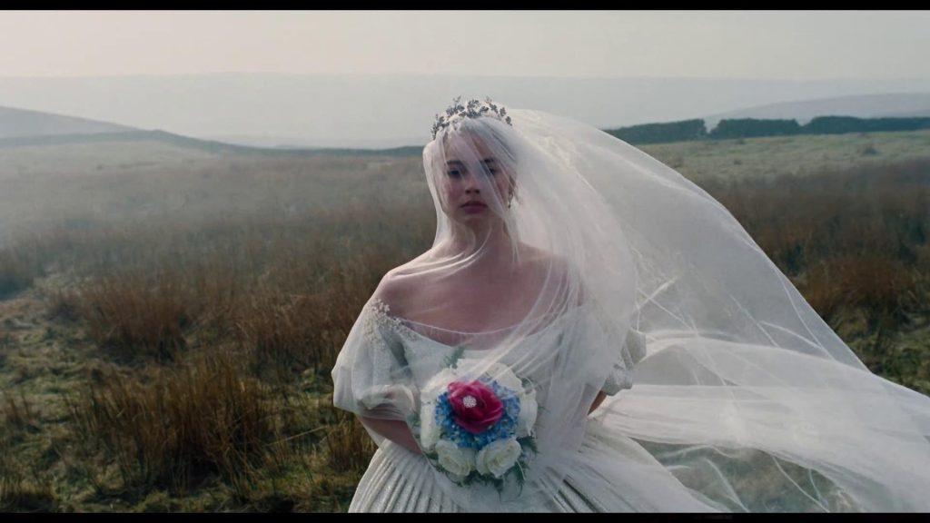 Fotograma de la película «Cumbres borrascosas»: una novia con vestido blanco, velo y ramo en un páramo brumoso