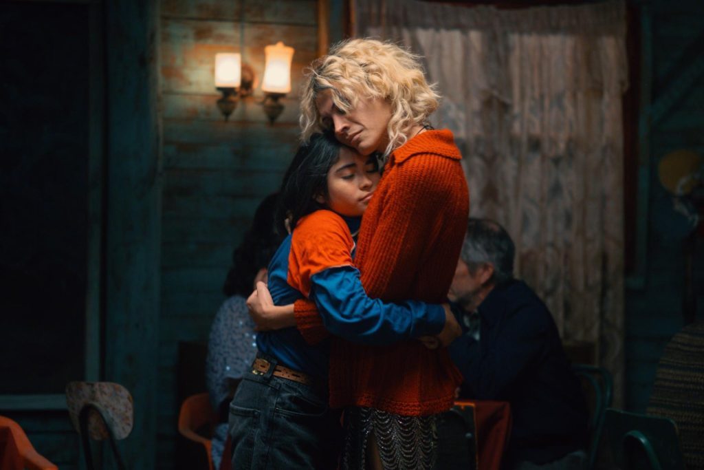Fotograma de la película «La misteriosa mirada del flamenco»: una mujer abraza a una niña en un interior con luz tenue