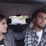 Dos personas en el interior de un vehículo, la mujer mira hacia el lado mientras el hombre conduce con expresión seria